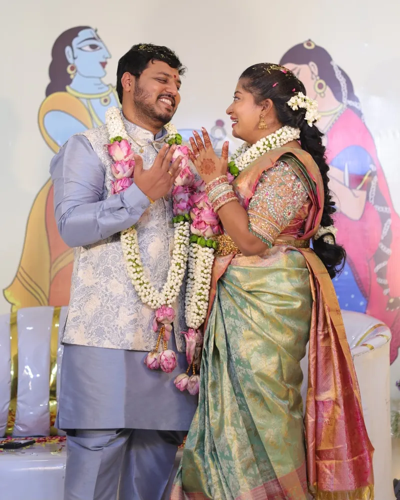 Susmita and Ashish laughing together, wearing garlands